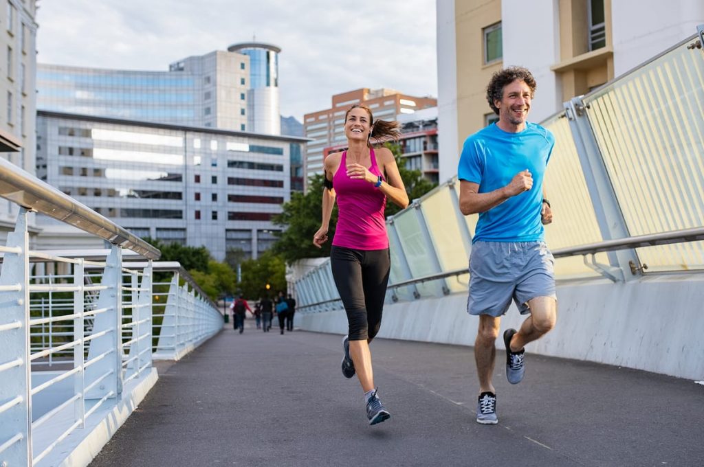 Beneficios de la actividad física para prevenir el cáncer Pareja corriendo al aire libre para mejorar la salud