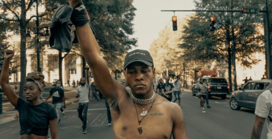La herencia del trauma: una lucha visible en las calles y en los genes. Manifestantes con el puño en alto como símbolo del trauma intergeneracional y la violencia que puede dejar marcas en el ADN.