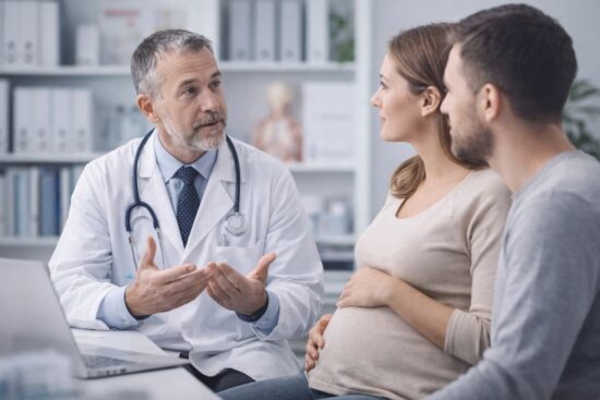 Médico explicando información sobre células madre a mujer embarazada y su pareja en consultorio